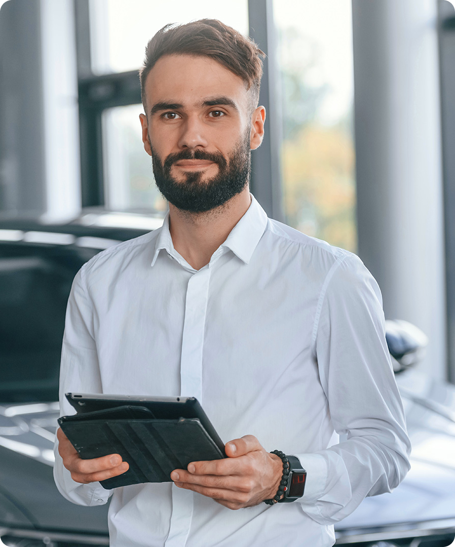 Man holding a tablet with car dealership in the background